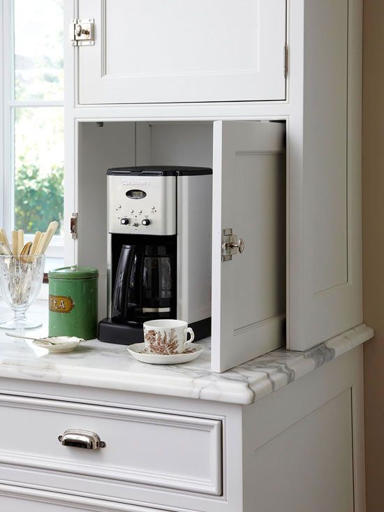 a coffee maker is sitting in the corner of a cabinet