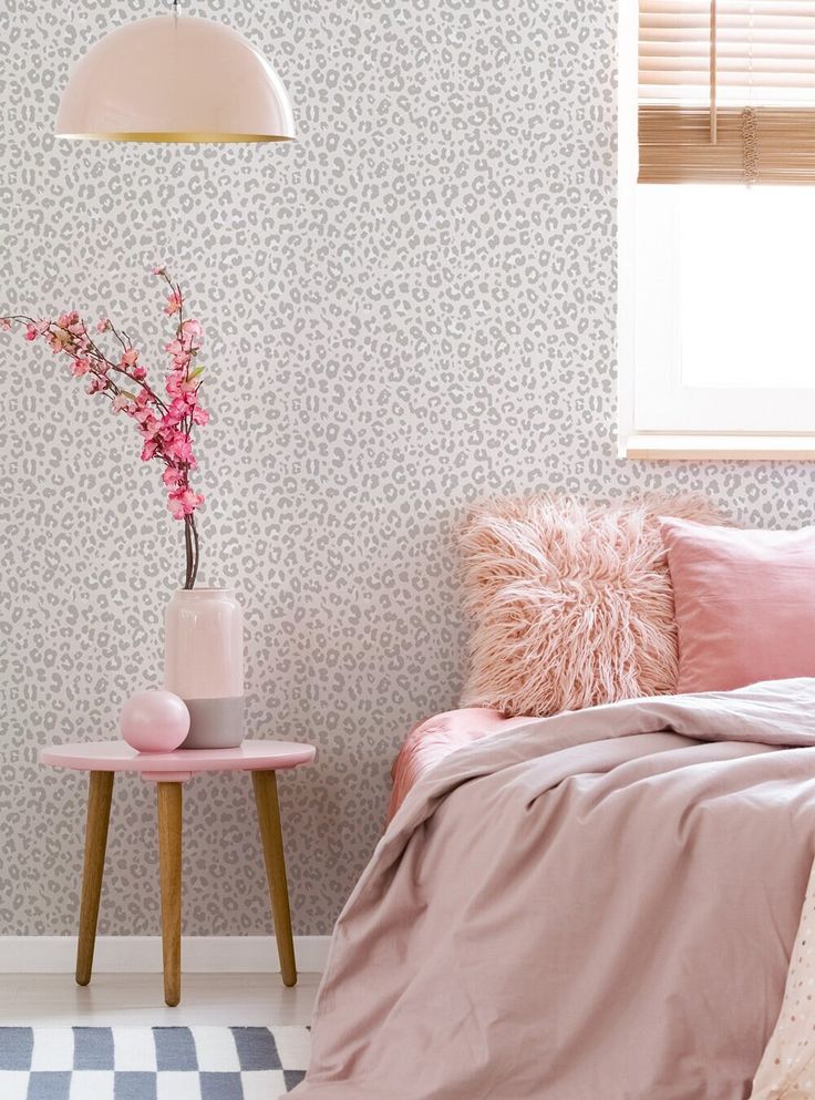 a bedroom with pink bedding and wall paper