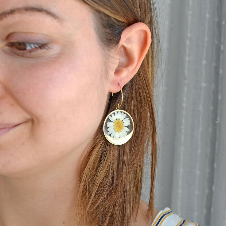 * Perhaps the most happy looking flower of them all! Round brass dangle earrings are holding a pressed white daisy to cheer you up with its sunny energy. * In most cultures daisies represent innocence, purity, new beginnings (which is why they are often found in bouquets for new mothers or as gifts for children) and true love (because each daisy flower is really two flowers blended together in harmony). * April's birth flowers * Total earring length approx. 5 cm (2 inches) * Each earring will sl Gold Daisy-shaped Jewelry For Summer, Gold Daisy Jewelry For Summer, Summer Daisy Flower Earrings Gift, Everyday Daisy Earrings, Gold Daisy Earrings With Flower Charm, Gold Daisy Flower Earrings As Gift, Handmade Gold Daisy Earrings, Nickel-free Daisy Flower Earrings Gift, Nickel-free Daisy Earrings For Gifts