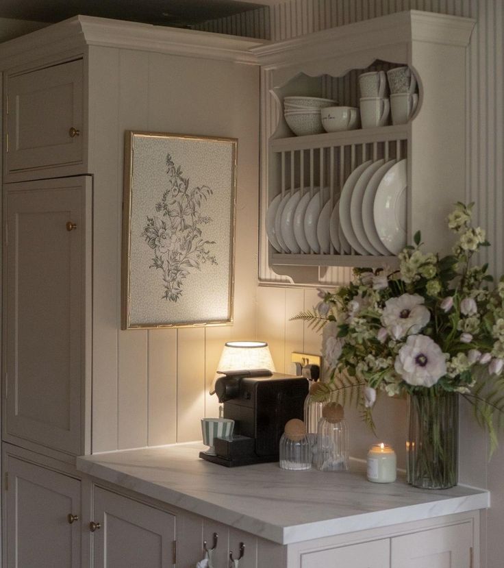 a kitchen with white cupboards and flowers on the counter top in front of it