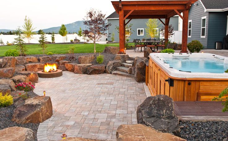 an outdoor hot tub surrounded by rocks and landscaping