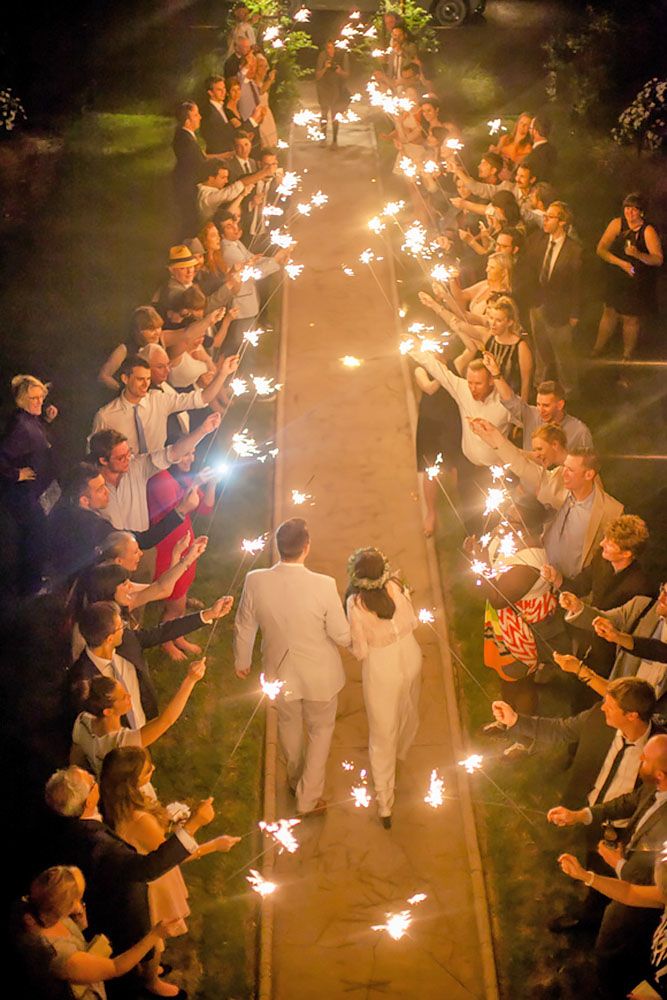 a bride and groom walking down the aisle holding sparklers