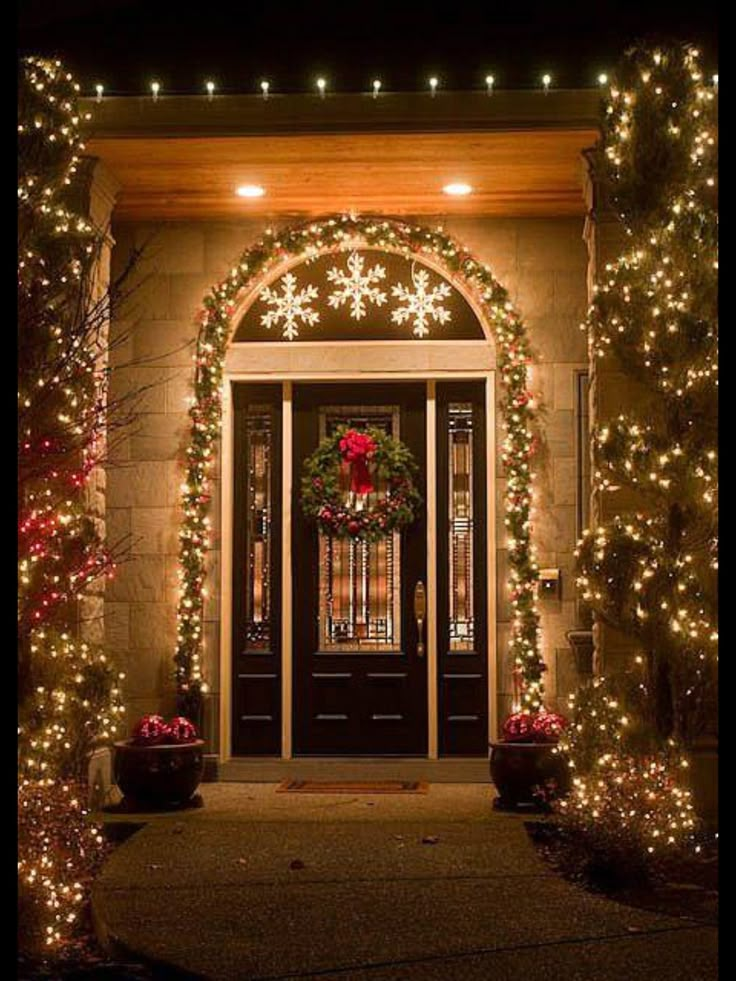 the front door is decorated with christmas lights and garlands for an elegant touch to any home