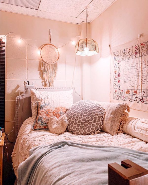 a bed with lots of pillows on top of it and lights above the headboard