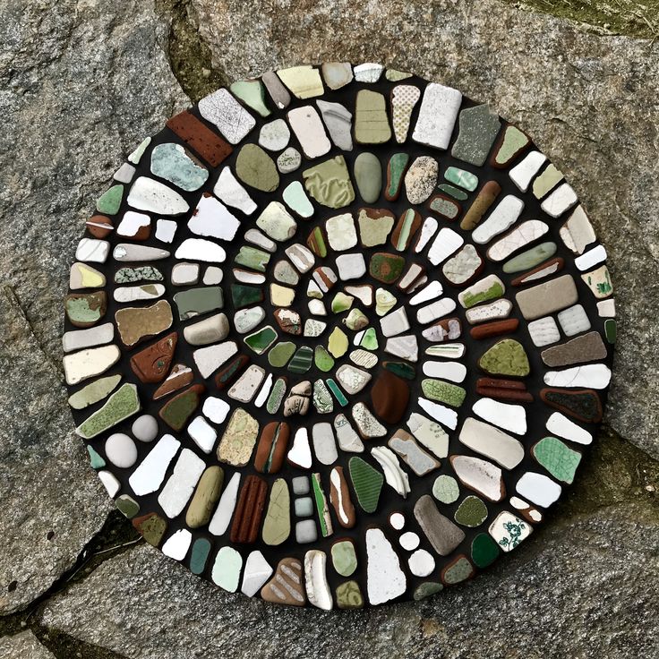 a circular piece of glass sitting on top of a stone wall covered in lots of different colored stones