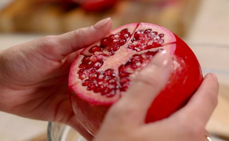 a person holding a piece of pomegranate in their hand