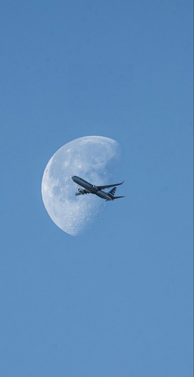 an airplane flying in front of the moon