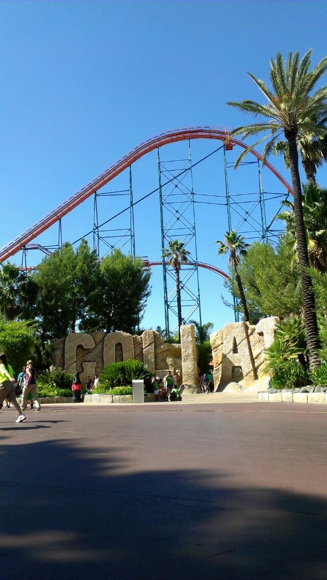 the roller coaster at universal studios in california city, ca with palm trees and people walking by