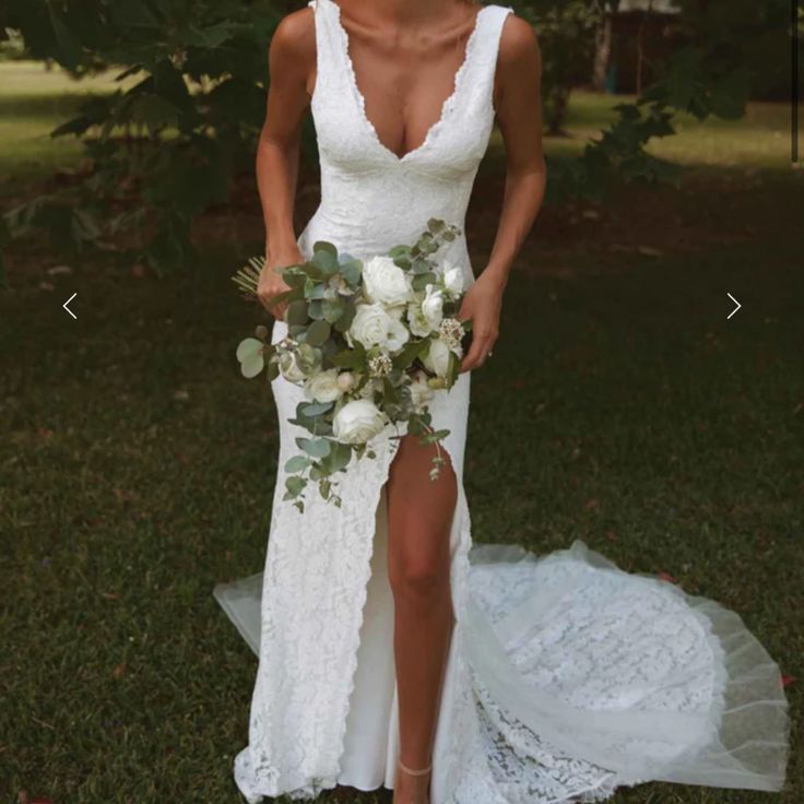 a woman in a white wedding dress holding a bridal bouquet and posing for the camera