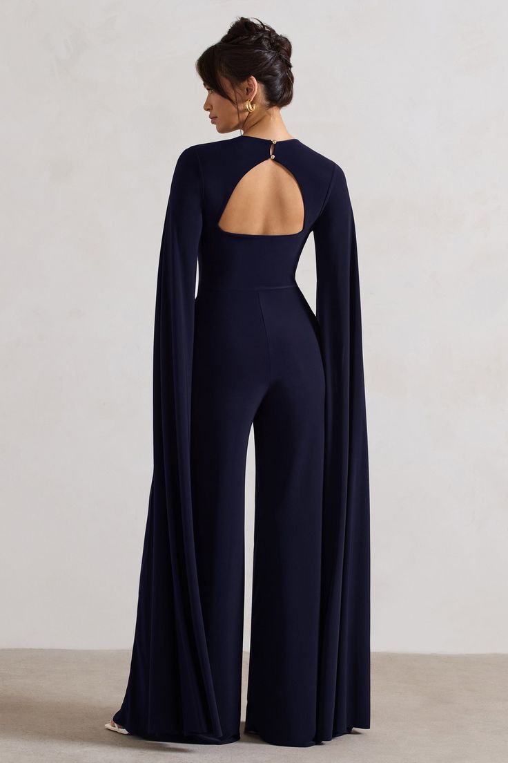 One of our favourite statement jumpsuits of the season, Emmanuela is an elegant ensemble for any formal event. Boasting a sculpting plunge neckline, what defines this flattering navy piece is floor sweeping cape sleeves and a contemporary cut-out back detail. For the perfect graduation look, team yours with some court shoes like Blade. Features - Premium stretch jersey- Plunge neckline - Cape sleeves- Button closure - Back cut out- Wide leg Sizing & Fit Model is 5'8 and wears UK size 8 / US size Fancy Jumpsuit Classy, Chic Event Outfit, Elegant Jumpsuits For Women, Jumpsuit Elegant Chic Classy, Outfit Ideas For Wedding Guest, Graduation Outfit Ideas For Guest, Eladrin Elf, Formal Event Outfit, Graduation Looks