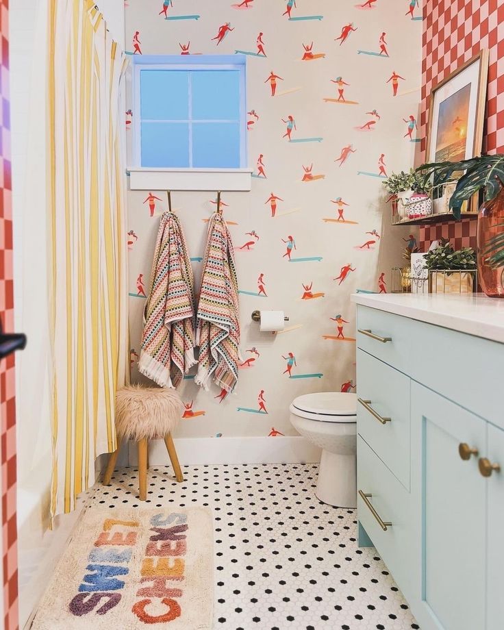 a bathroom with red and white checkered wallpaper, two towels hanging on the rack