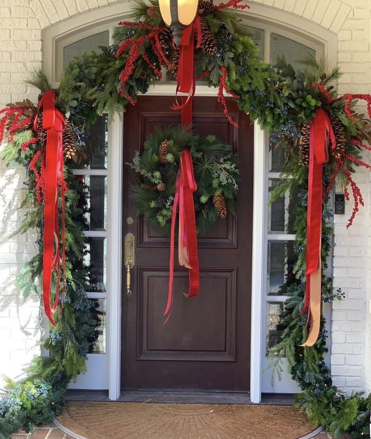 the front door is decorated for christmas with wreaths and lights