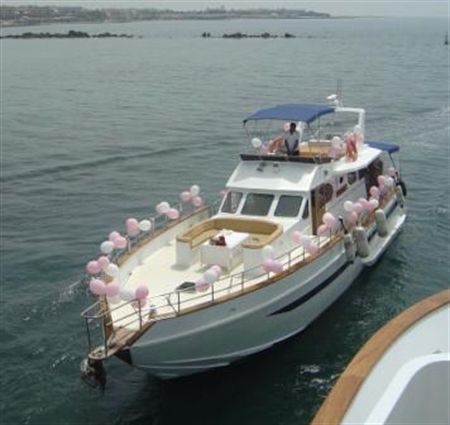 a white boat with balloons on it floating in the water