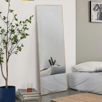 a large mirror sitting on top of a bed next to a plant