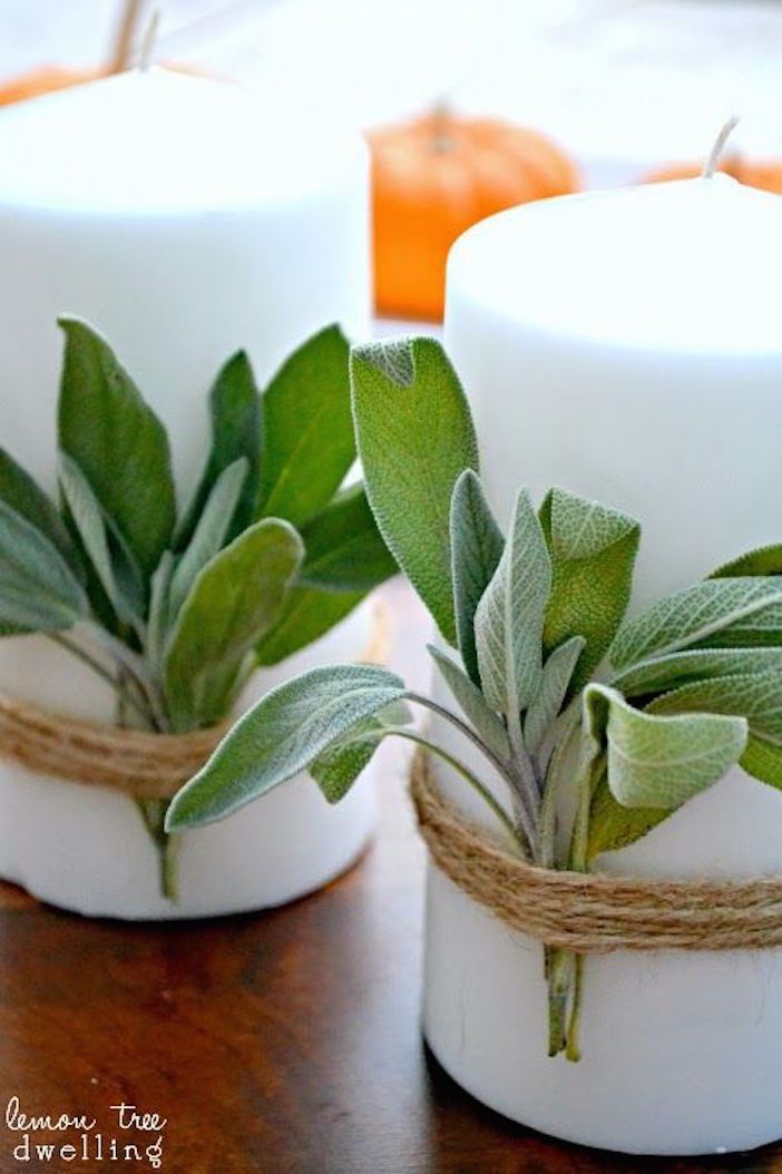 two white candles with green leaves tied to them