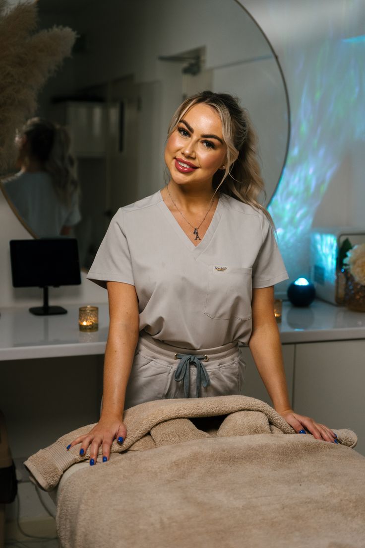 a woman sitting on top of a bed in a room next to a table with a mirror