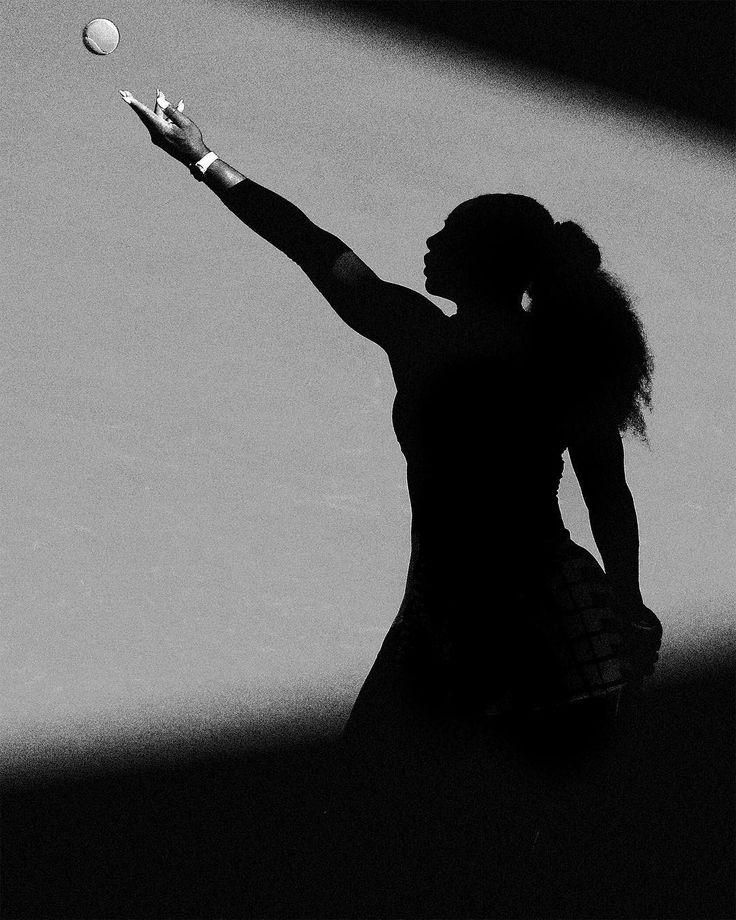 a black and white photo of a woman serving a tennis ball