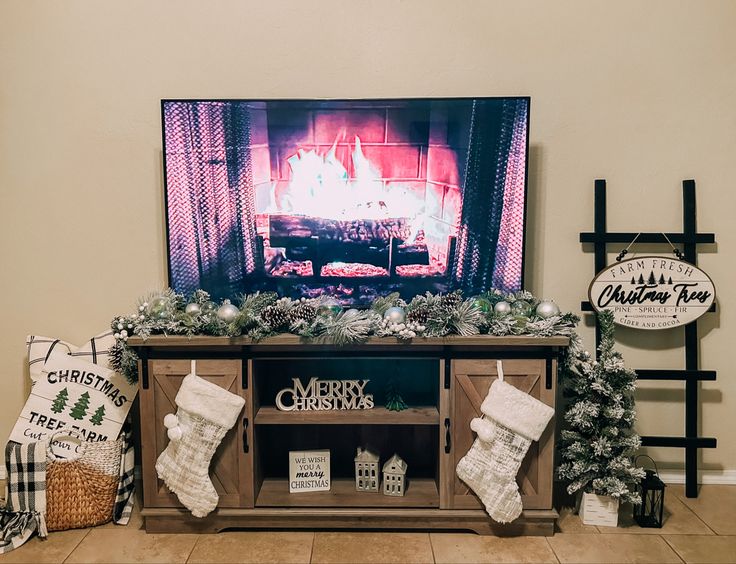 a christmas fireplace decorated with stockings, stockings and other holiday decorations in front of a flat screen tv