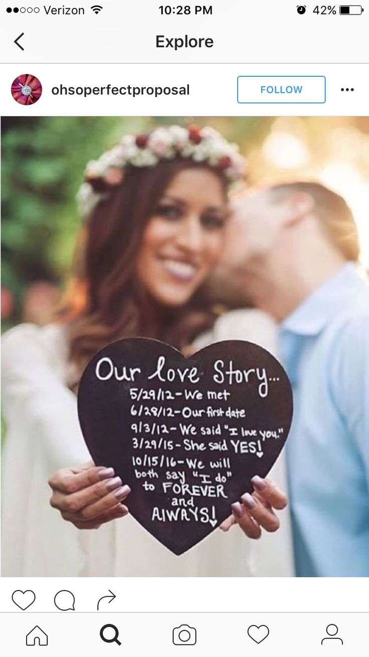 a man and woman kissing while holding up a heart shaped sign with the words our love story written on it