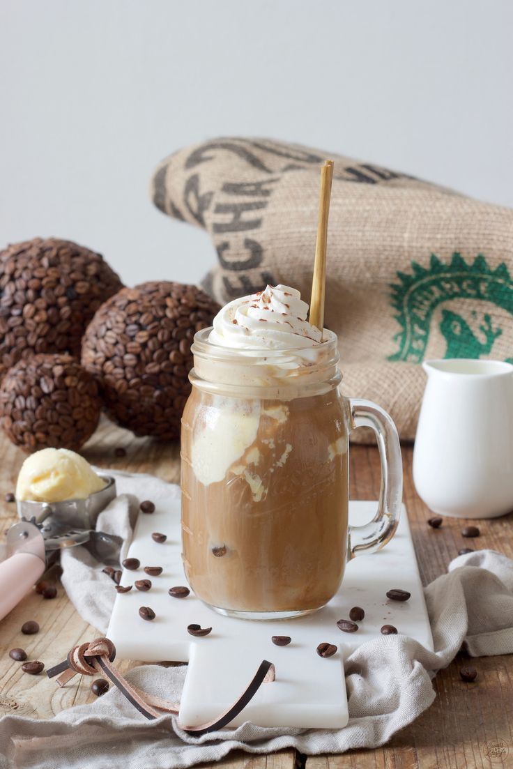 an iced coffee drink with whipped cream and chocolate chips on a napkin next to some cookies