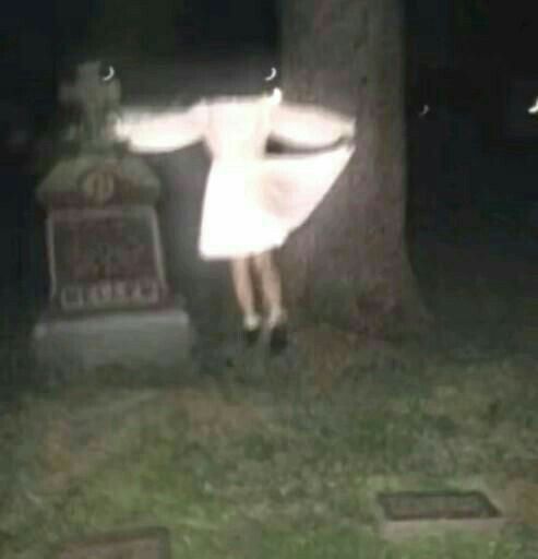 a woman standing in front of a tree at night