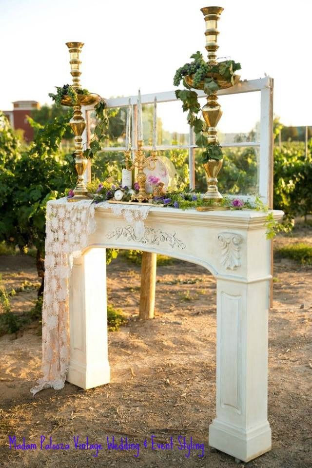 a white mantle with flowers and candles on it in the middle of a dirt field