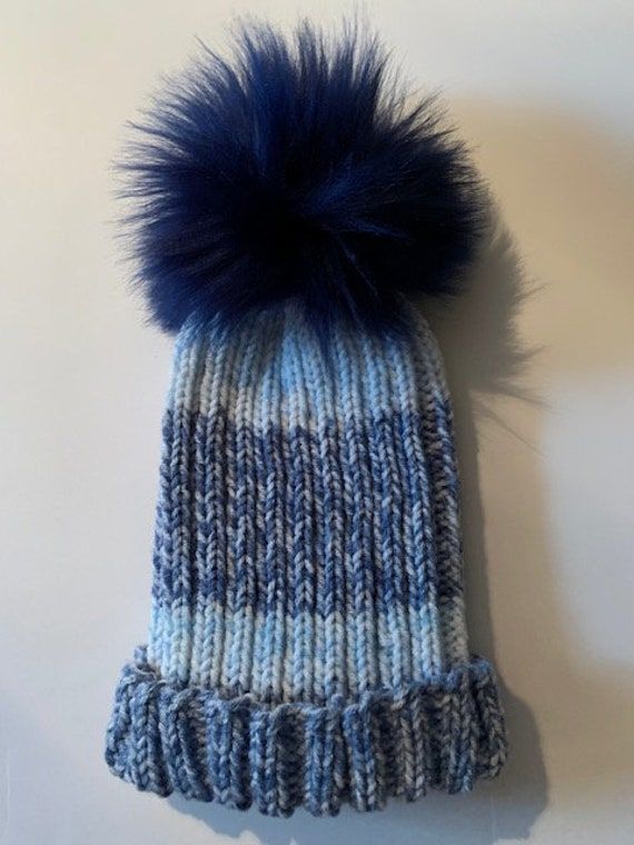 Cute and fashionable knitted hat made with the softest yarn in a warm thick-stitch knit. Acrylic/alpaca/wool/viscose. Topped with a large blue faux-fur pompom. Warm Blue Beanie For Winter, Blue Knit Beanie For Winter, Blue Knit Beanie Hat, Blue Wool Knitted Beanie, Winter Alpaca Soft Knit Hat, Blue Soft Knit Beanie For Fall, Blue Knit Beanie For Cold Weather, Blue Beanie Hat For Winter, Winter Soft Knit Alpaca Hat