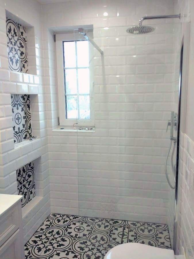 a white bathroom with black and white tile on the floor, shower stall and toilet