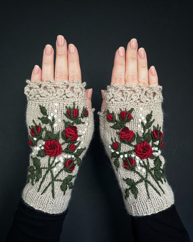 a woman's hands wearing knitted gloves with roses and leaves on the fingers