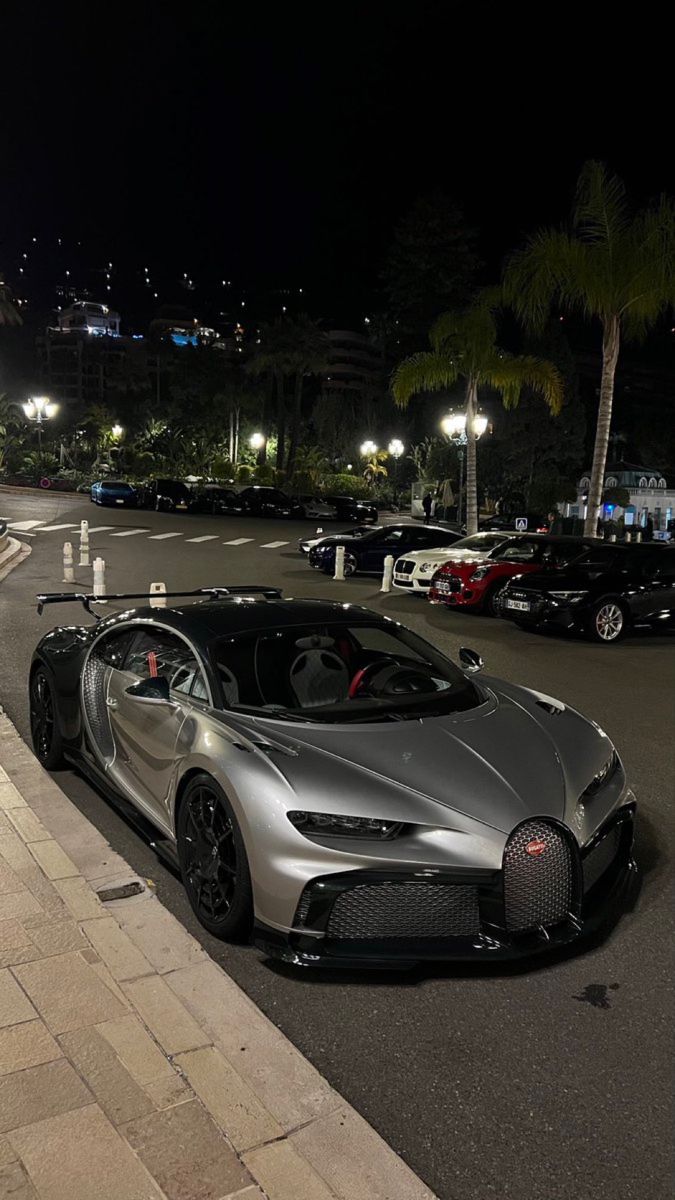 a silver bugatti parked on the side of a road next to a parking lot