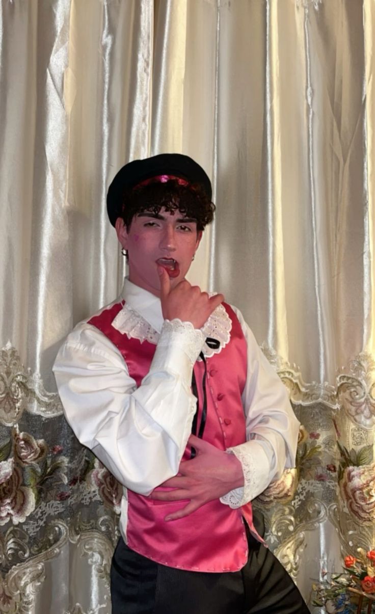 a man in a pink and white outfit is posing for the camera with his finger on his mouth