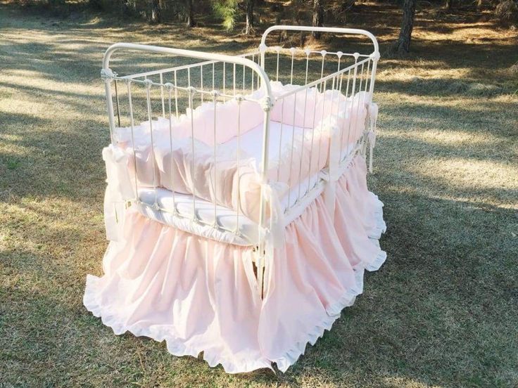 an old crib is covered in pink ruffles and sits on the grass