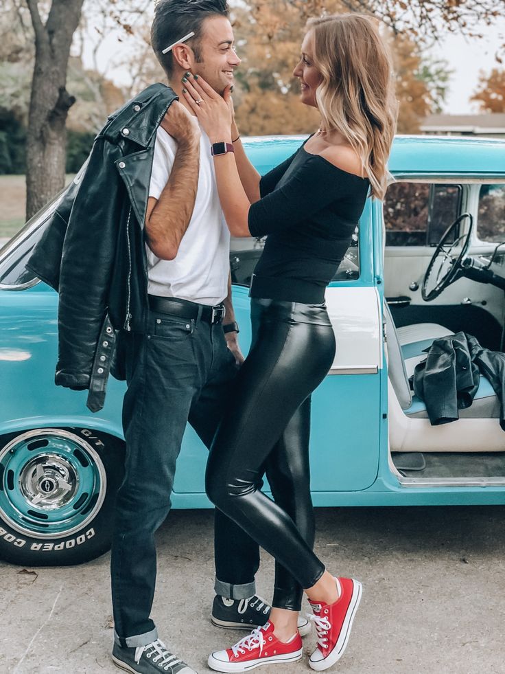 a man and woman standing in front of a blue car