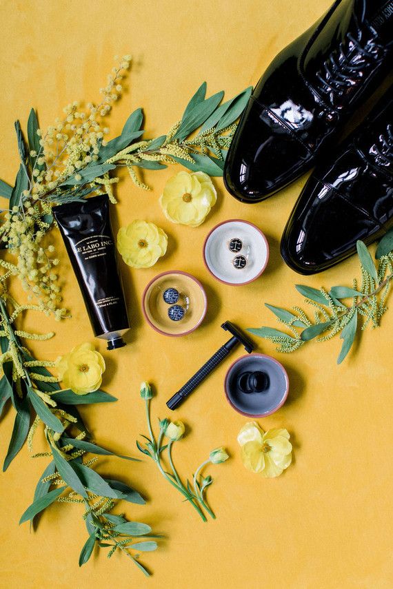 black shoes and yellow flowers on a yellow surface with buttons, pins, and other items