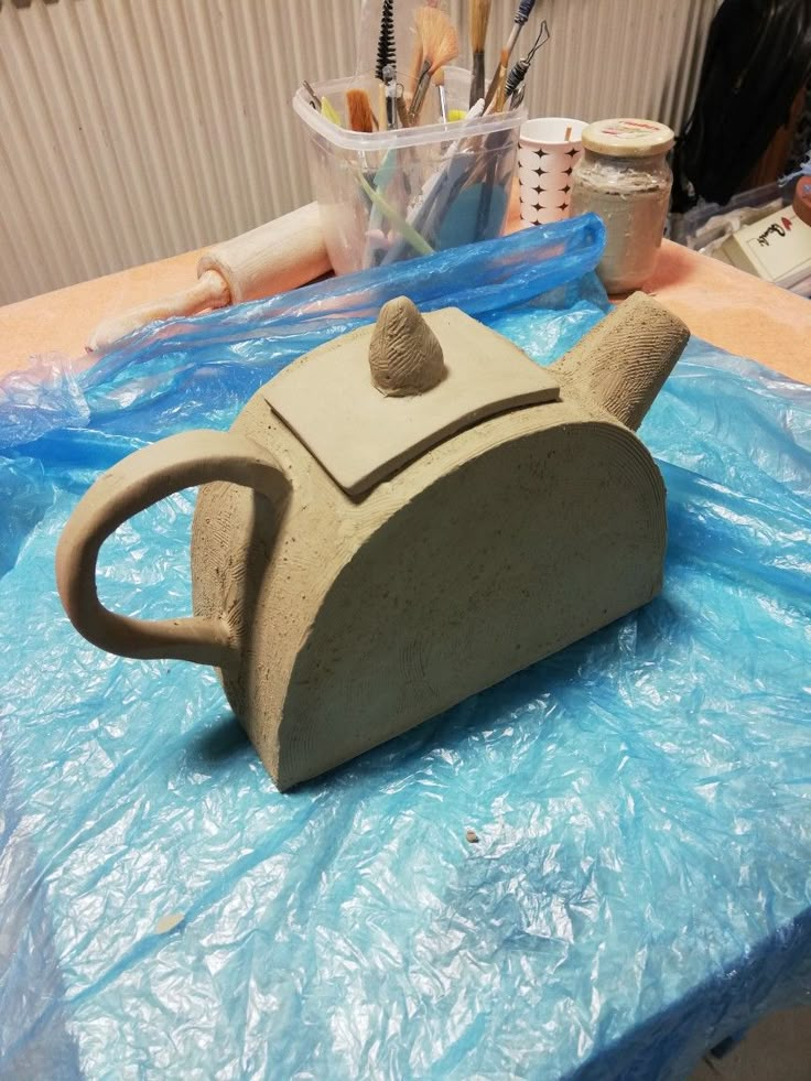 a stone teapot sitting on top of a table covered in plastic