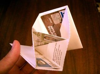 an origami wallet is held open to show the money inside