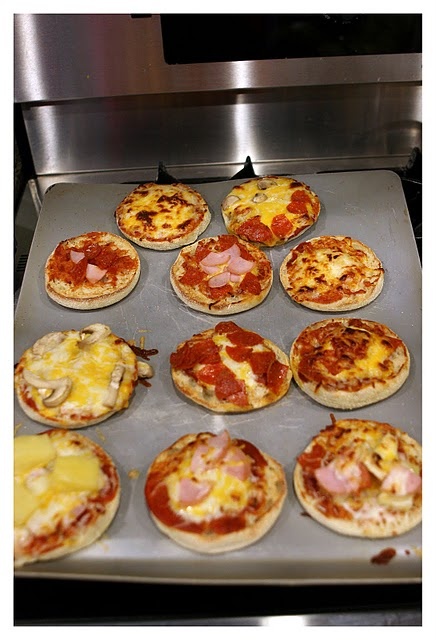 mini pizzas sitting on top of a pan in the oven, ready to be cooked