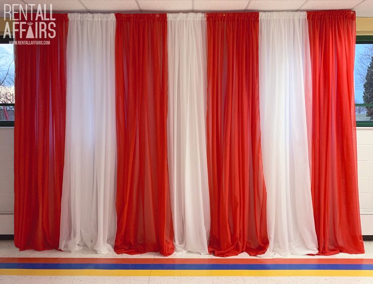 red and white curtains are hanging in front of a window