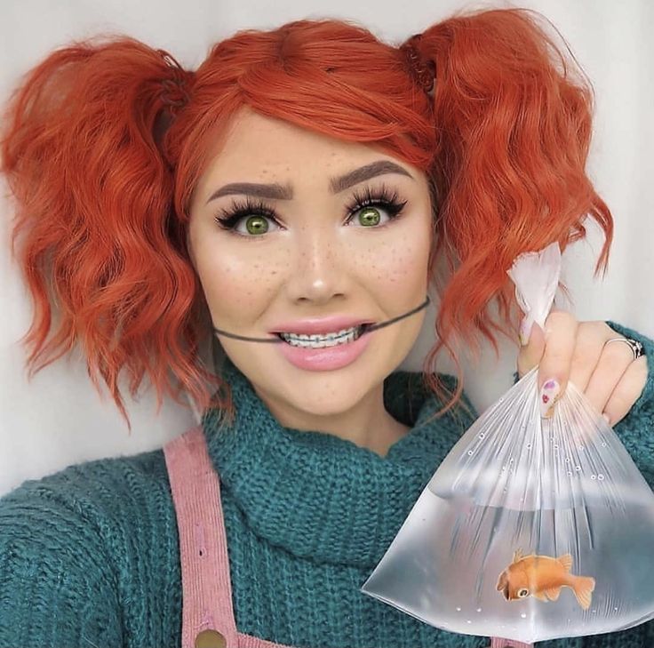 a woman with red hair and green eyes holding a plastic bag filled with fish in it