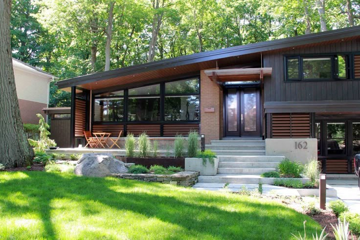 a modern house in the woods with grass and trees