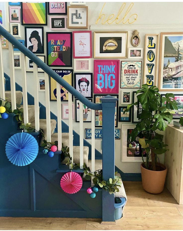 there is a staircase decorated with pictures and decorations on the wall next to potted plants