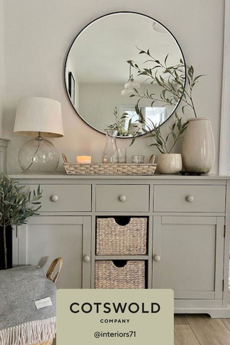 a gray dresser with baskets on top and a mirror above it