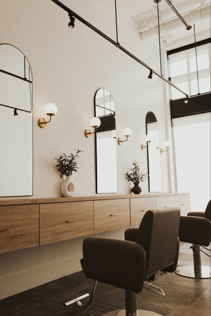 a hair salon with chairs, mirrors and lights on the wall in front of them