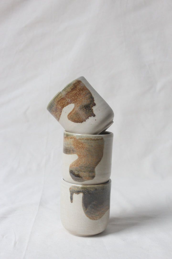 three ceramic cups stacked on top of each other in front of a white background,