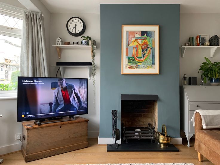 a flat screen tv sitting on top of a wooden stand next to a fire place