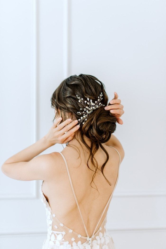 the back of a woman's head wearing a bridal hair piece with pearls on it