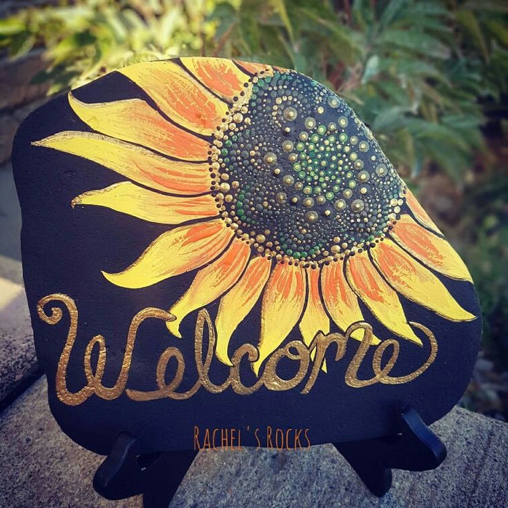 a sunflower painted on the side of a welcome sign