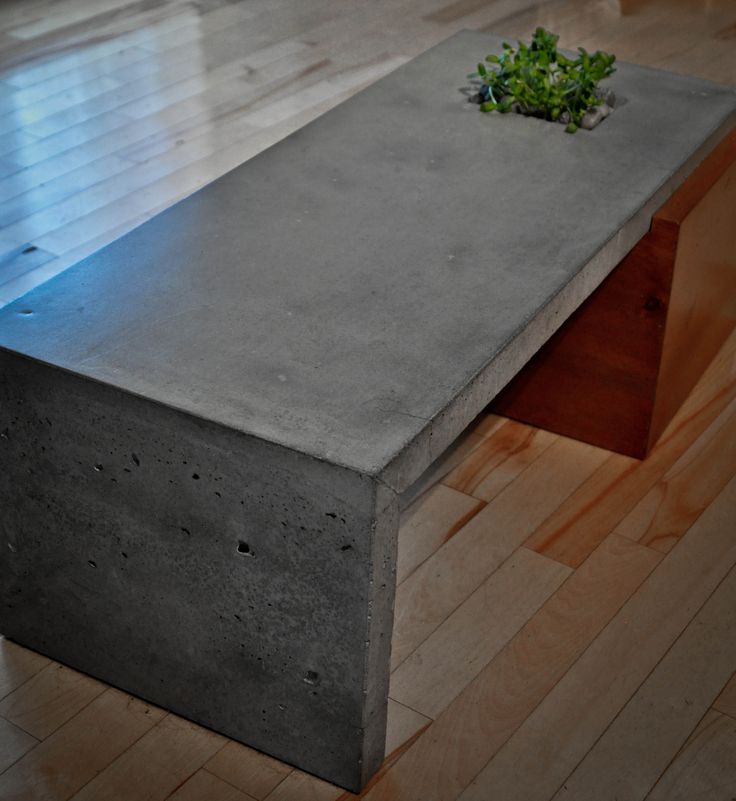 a concrete bench sitting on top of a hard wood floor next to a planter