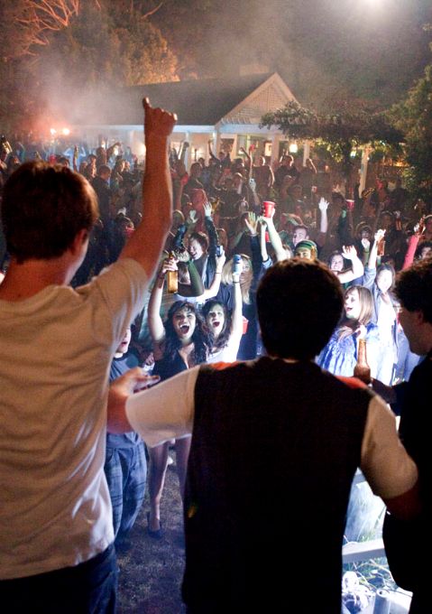 a group of people standing in front of a crowd at a music festival with their hands up