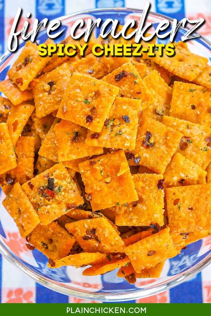 a glass bowl filled with cheesy crackers on top of a checkered table cloth